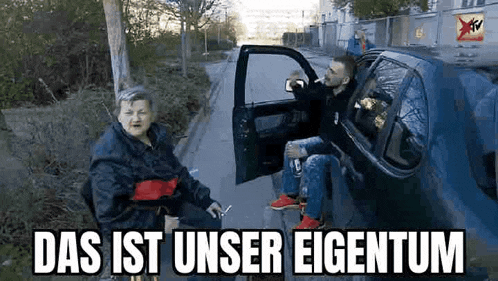 an elderly woman is sitting in a wheelchair next to a man sitting in a car .