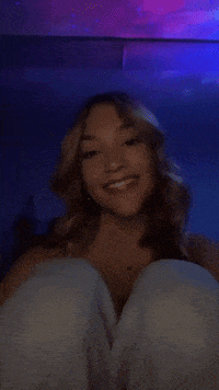 a woman is sitting with her legs crossed and smiling in front of a blue light