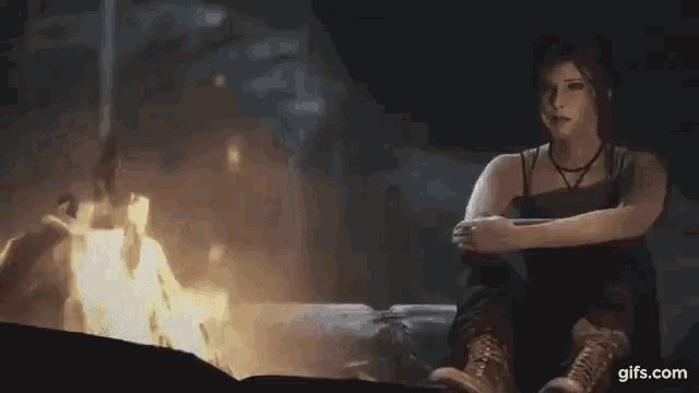 a woman is sitting in front of a fire in the dark .