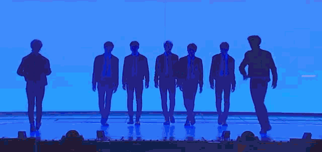 a group of people are standing on a stage in front of a large screen with the word enhypen written on it .