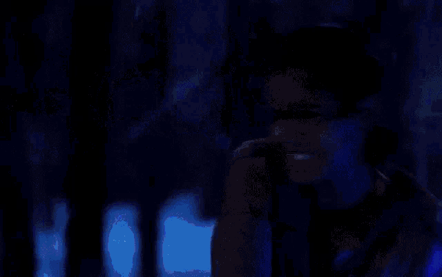 a person is holding a blue light saber in the dark .