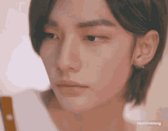 a close up of a young man 's face with long hair looking at the camera .