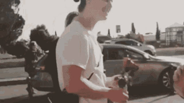 a man is holding a red rose in his hand in front of a car .