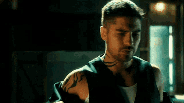 a man with a tattoo on his arm is wearing a black vest .