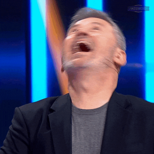 a man in a suit is laughing with his mouth open in front of a sign that says passworst