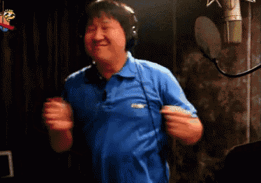 a man wearing headphones and a blue shirt is dancing in front of a microphone ..