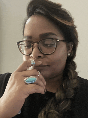 a woman with glasses and a turquoise ring on her finger