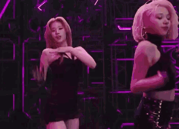 a group of women are dancing on a stage in front of a purple light .