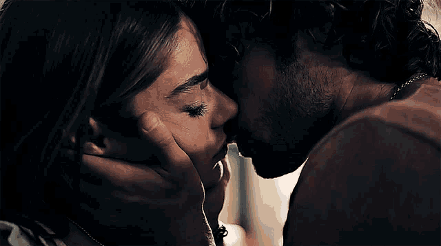 a close up of a man kissing a woman on the nose