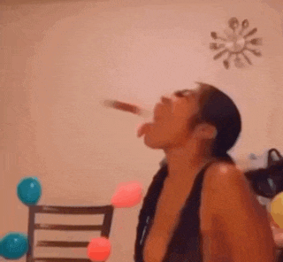 a woman is drinking from a bottle in a room with balloons and a clock on the wall .