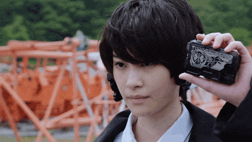 a person holding a device that says ' kamen rider zero two ' on it