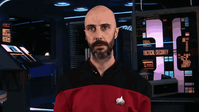 a man in a star trek uniform stands in front of a tactical security screen