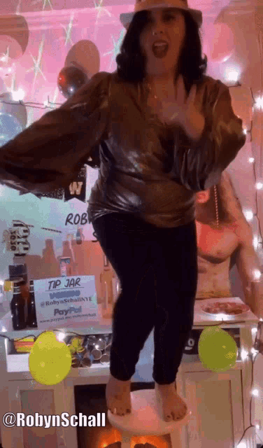 a woman is dancing in front of a sign that says tip jar on it