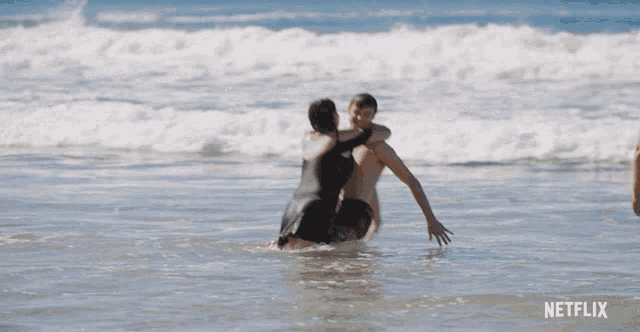 a man in blue shorts is standing in the ocean with a netflix logo on the bottom right