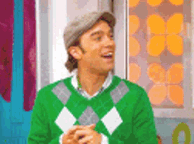 a man in a green sweater and hat is smiling