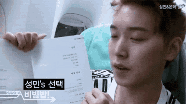 a man is holding a piece of paper with a foreign language written on it