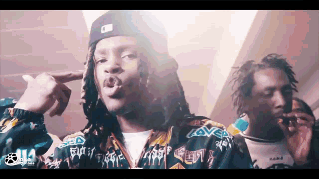 a man with dreadlocks is wearing a jacket that says loved on it