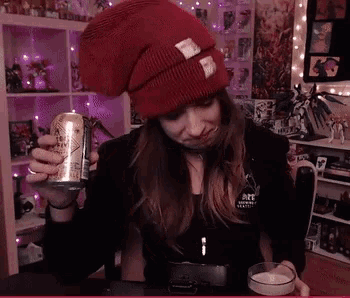 a woman in a red hat holds a can of beer