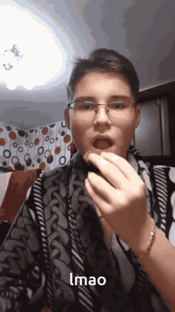 a young man wearing glasses and a bracelet is eating something