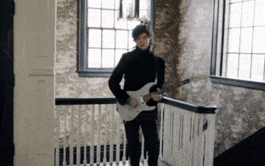 a man in a black suit is playing a guitar on a staircase