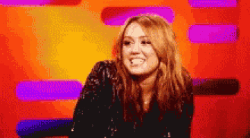 a woman in a sequined jacket is smiling in front of an orange and purple background