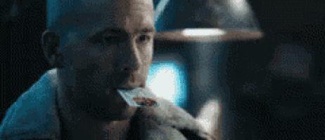 a man is brushing his teeth in a dark room while holding a toothbrush in his mouth .
