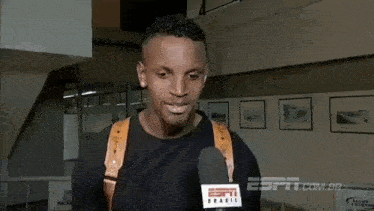 a man is talking into a microphone in a room with pictures on the wall .