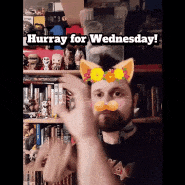 a man says hurray for wednesday in front of a shelf full of books