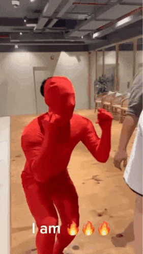 a person in a red bodysuit is dancing in a room with fire signs behind them .