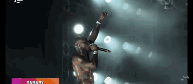 a shirtless man singing into a microphone with the name daraby behind him