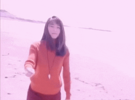 a woman with long hair is smiling and taking a selfie on the beach .