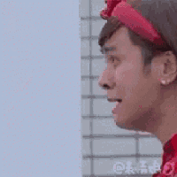 a man wearing a red shirt and a red hat is looking down .