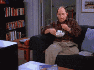 a man is sitting on a couch eating popcorn and watching tv