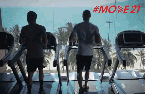 two men are running on treadmills in front of a window with #mode21 written in red