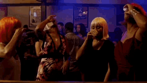 a group of women in wigs are dancing in a bar .