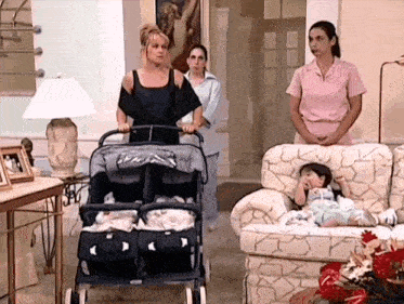 a woman pushing a stroller with three babies in it in a living room