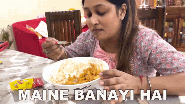 a woman sits at a table eating a bowl of food with the caption " maine banayi hai "