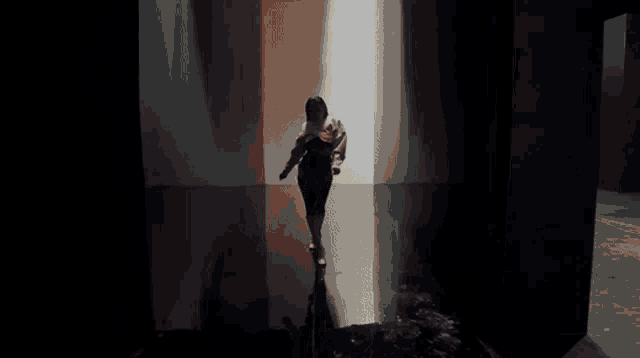 a woman in a black dress is walking down a hallway