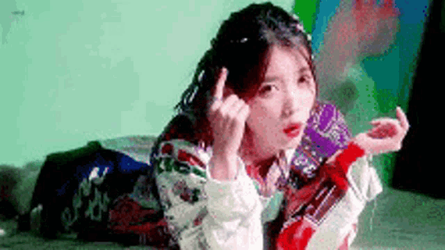 a woman is laying on her stomach on a bed giving the middle finger .