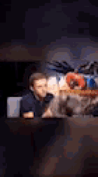 a blurry picture of a man sitting at a table with a bunch of stuffed animals on it .