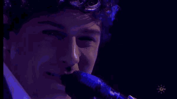 a close up of a person singing into a microphone on a stage .