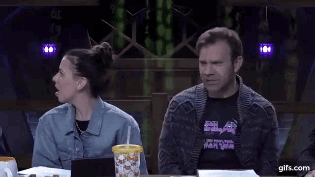 a man and a woman are sitting at a table and the man says you monster