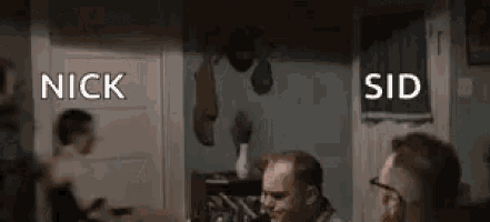 a group of men are sitting at a table in a room and talking .