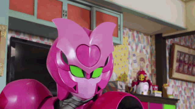 a pink robot with green eyes is in a room