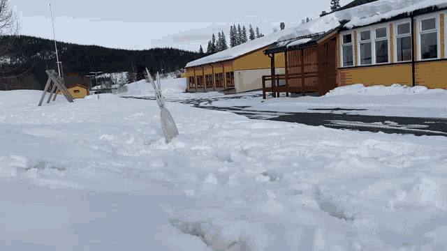 a snowmobile is parked in the snow in front of a yellow building