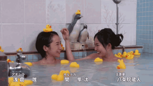 two women in a bathtub with rubber ducks on their head
