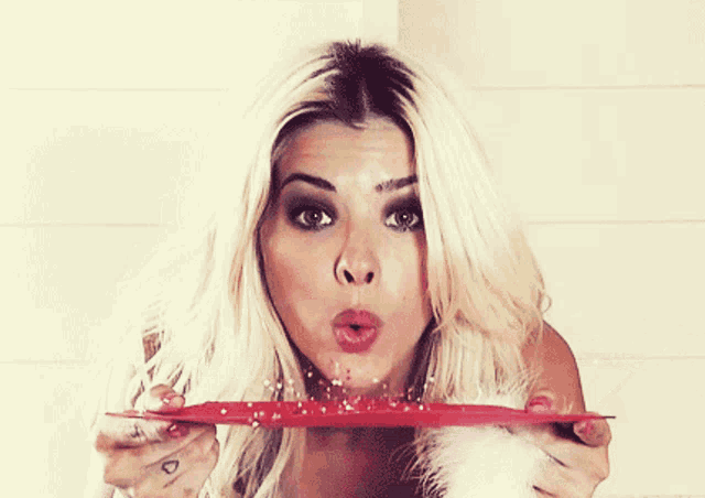 a woman blowing a kiss while holding a red plate