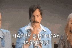 a man with a mustache is sitting in front of a group of people and says `` happy birthday jasmine '' .