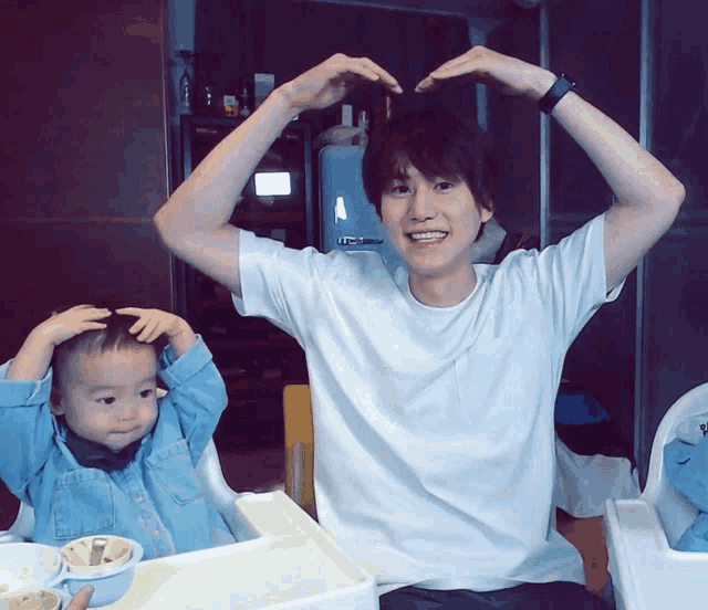 a man and a child are making a heart shape with their arms