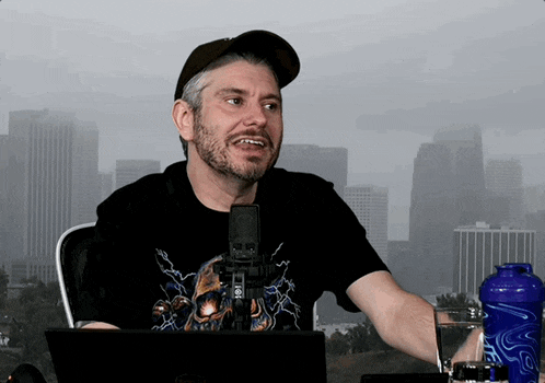 a man in a black shirt with a skull on it is sitting in front of a microphone
